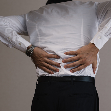 痛む腰を抑える男性